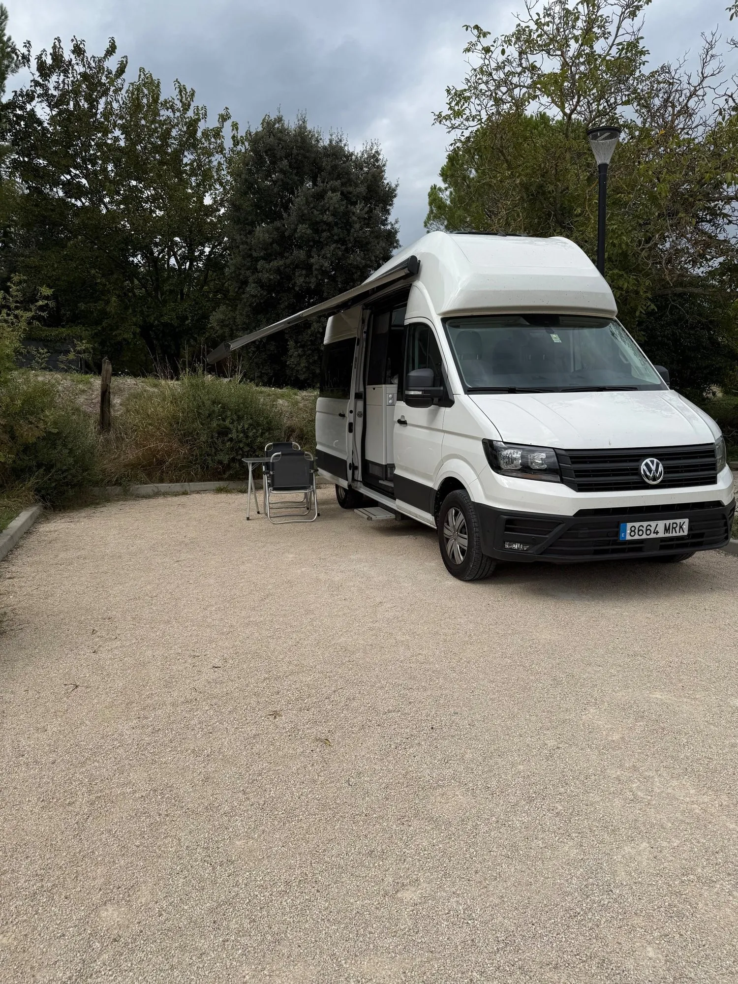Motorhome branco estacionado entre árvores