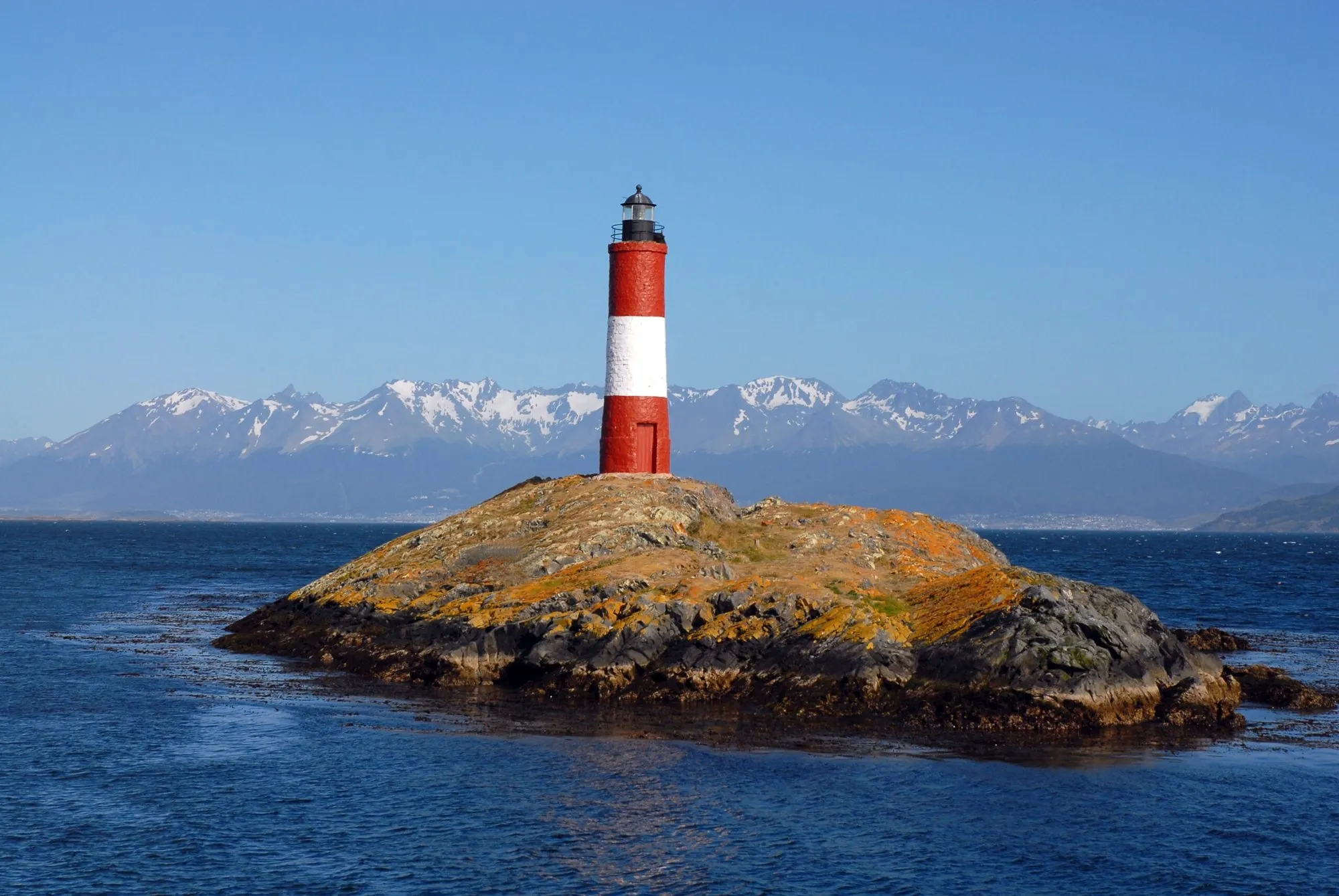 Farol listrado de vermelho e branco sobre uma ilha rochosa no Canal de Beagle